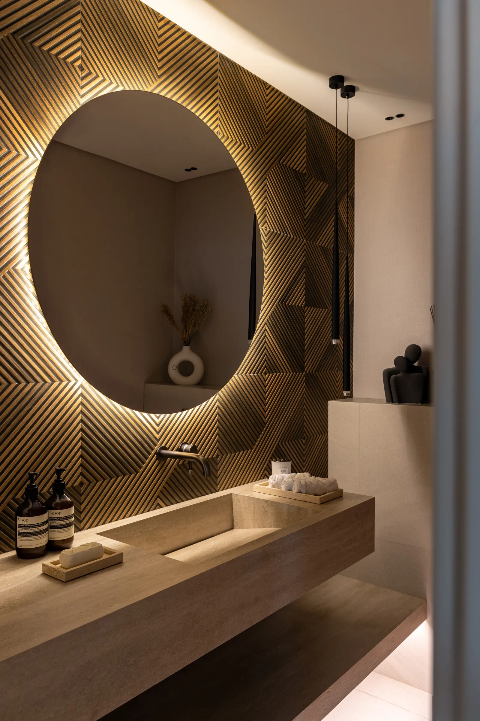 Twyst Interiors.Turk Villa primary bathroom with twin backlit mirrors, warm stone vanity, brushed black fittings.